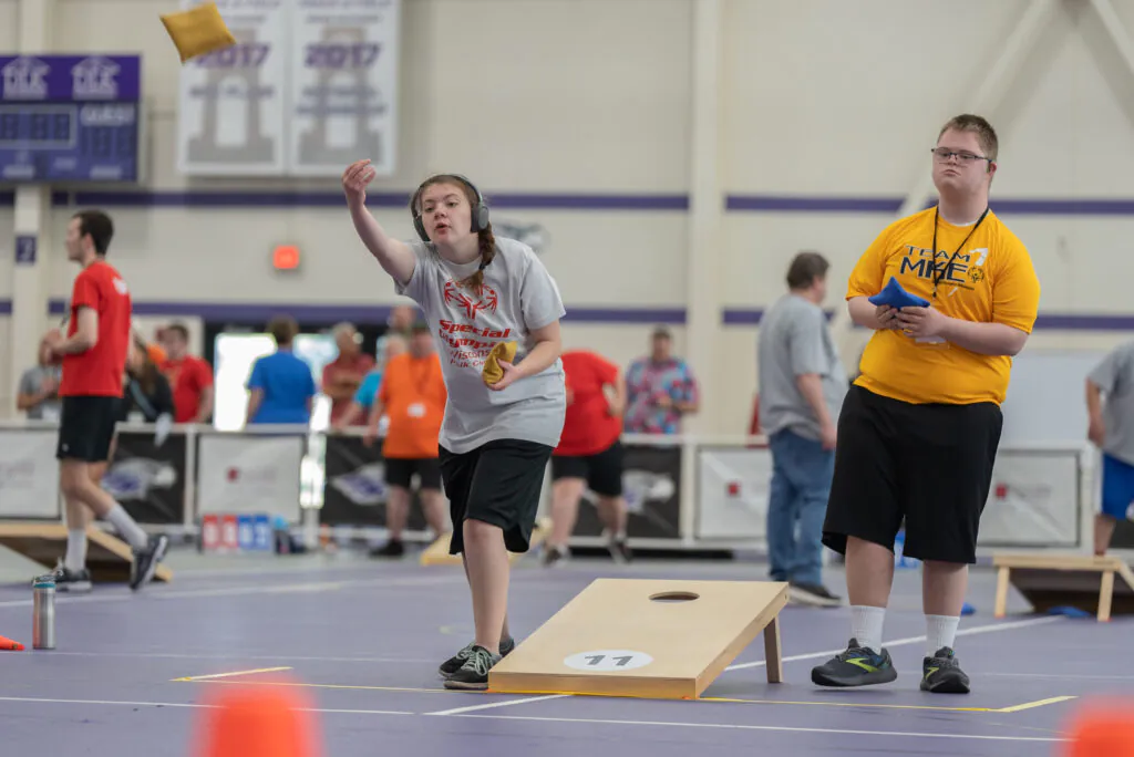 two athletes playing corhnole