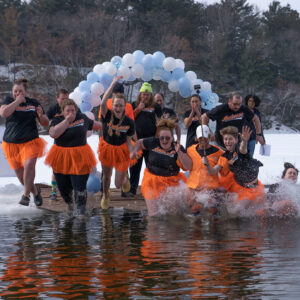team wearing orange and black plunge from ice into lake